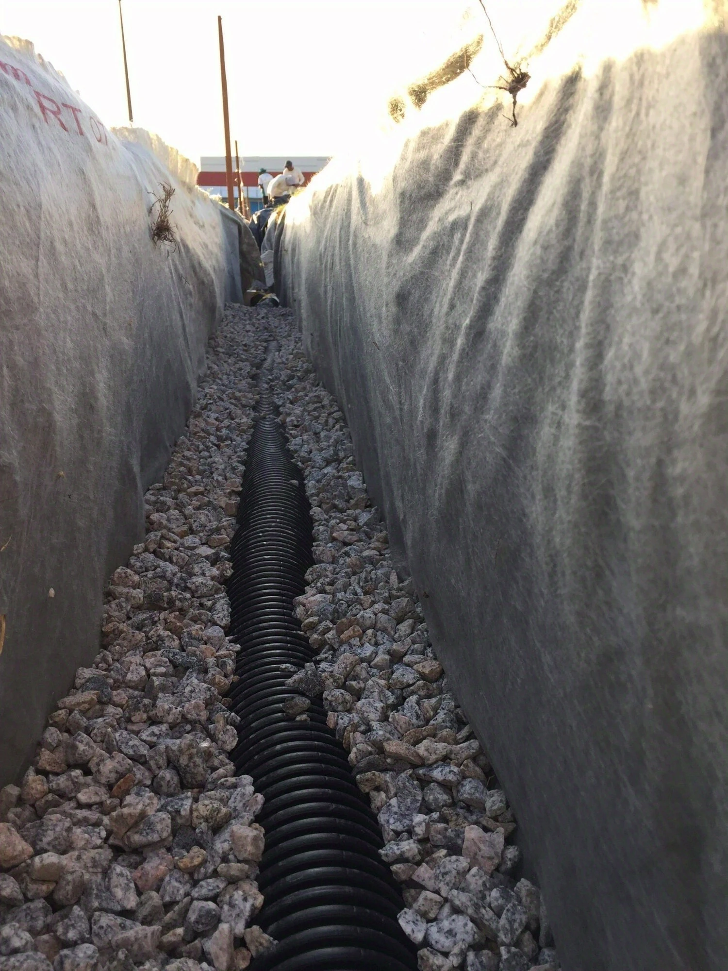 Techdreno drainage pipe laid on gravel and wrapped in geotextile within the trench